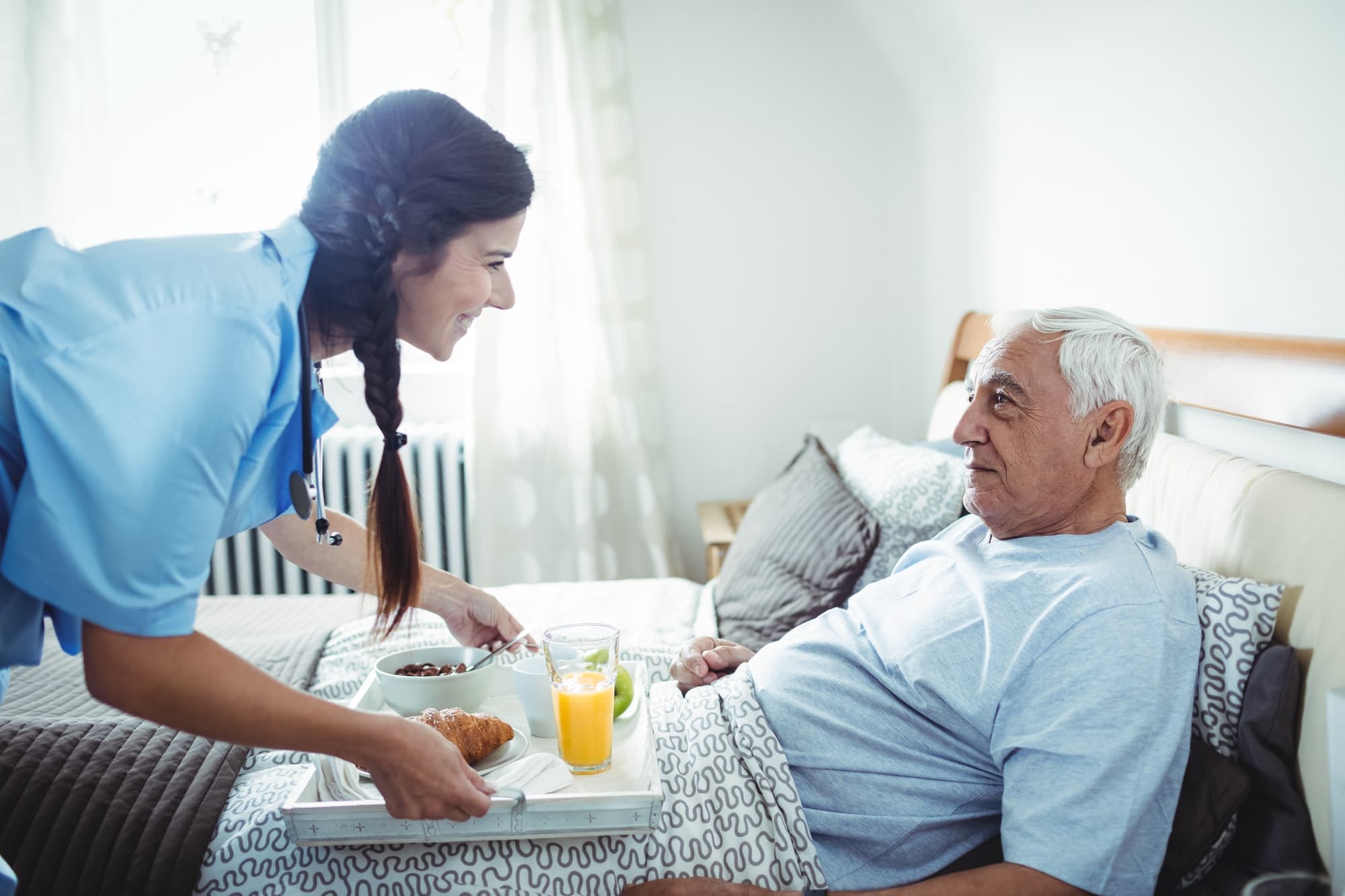 A care worker serving breakfast to an older man at home